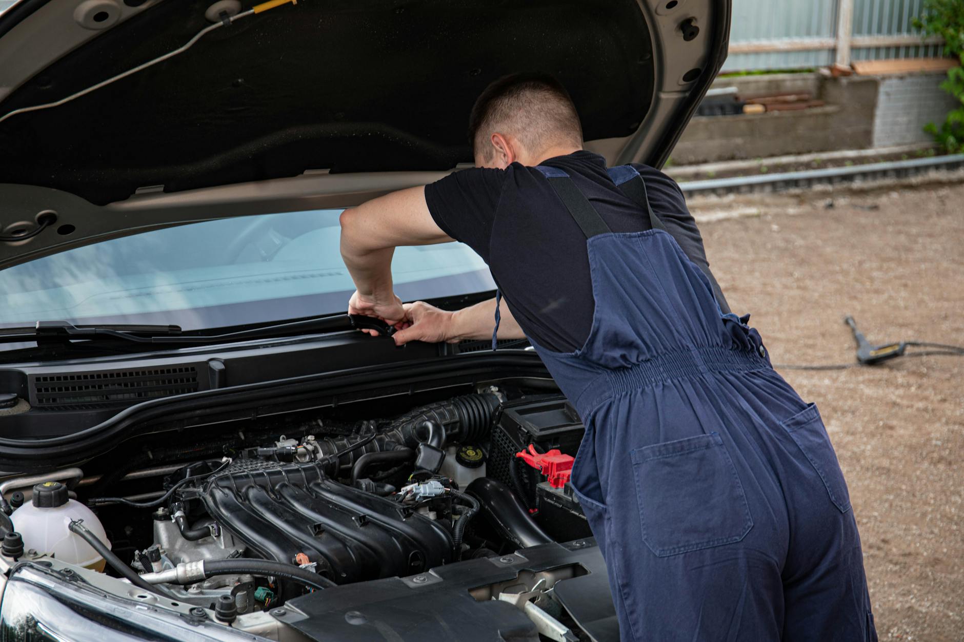 Mechanik naprawiający silnik auta po wypadku na zewnątrz latem