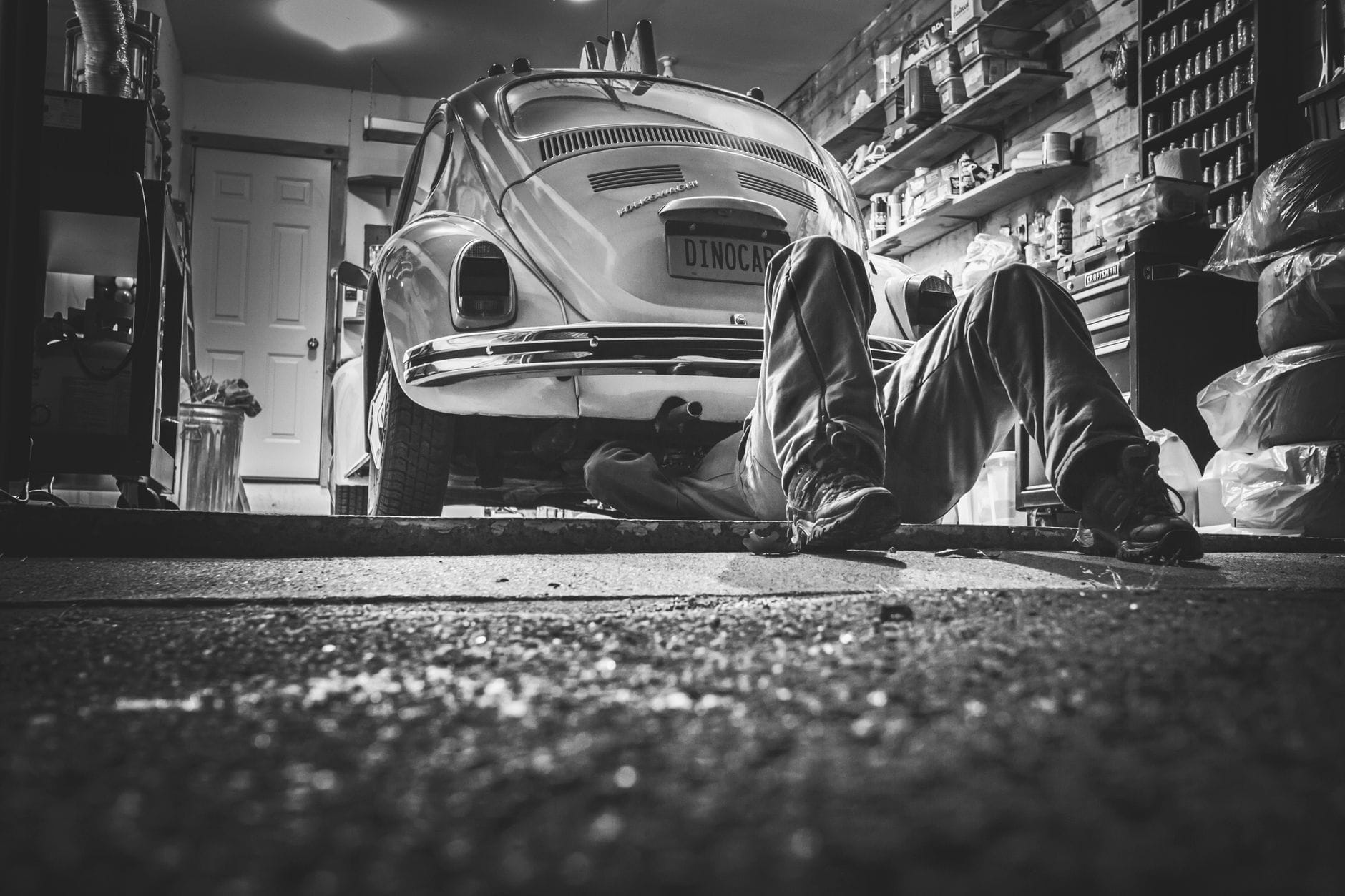 Mechanik pracujący pod klasycznym garbusem w przydomowym garażu