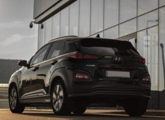 Tył czarnego Hyundaia Kona zaparkowanego przy szklanym budynku